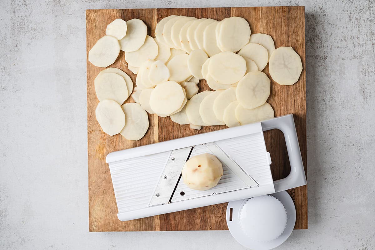 potato being sliced using a mandoline