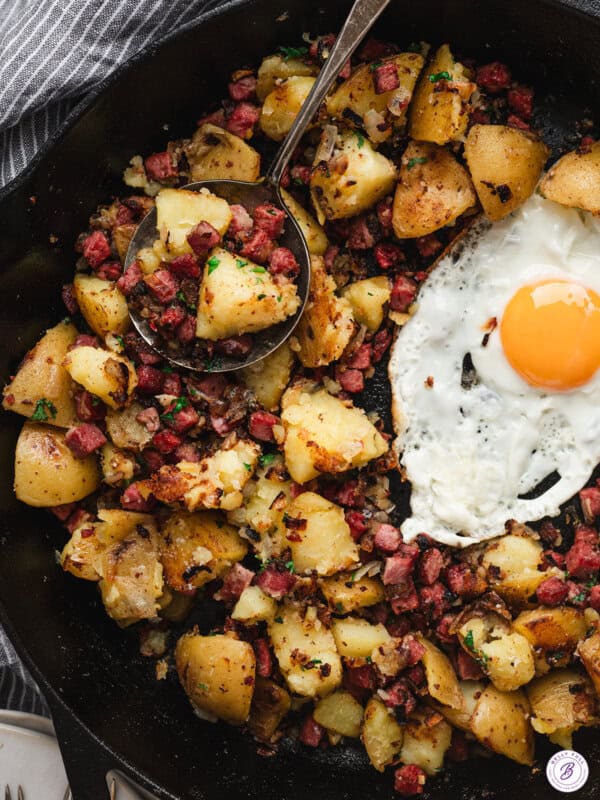 Corned beef hash in cast iron skillet with crispy potatoes, diced corned beef, and fried egg