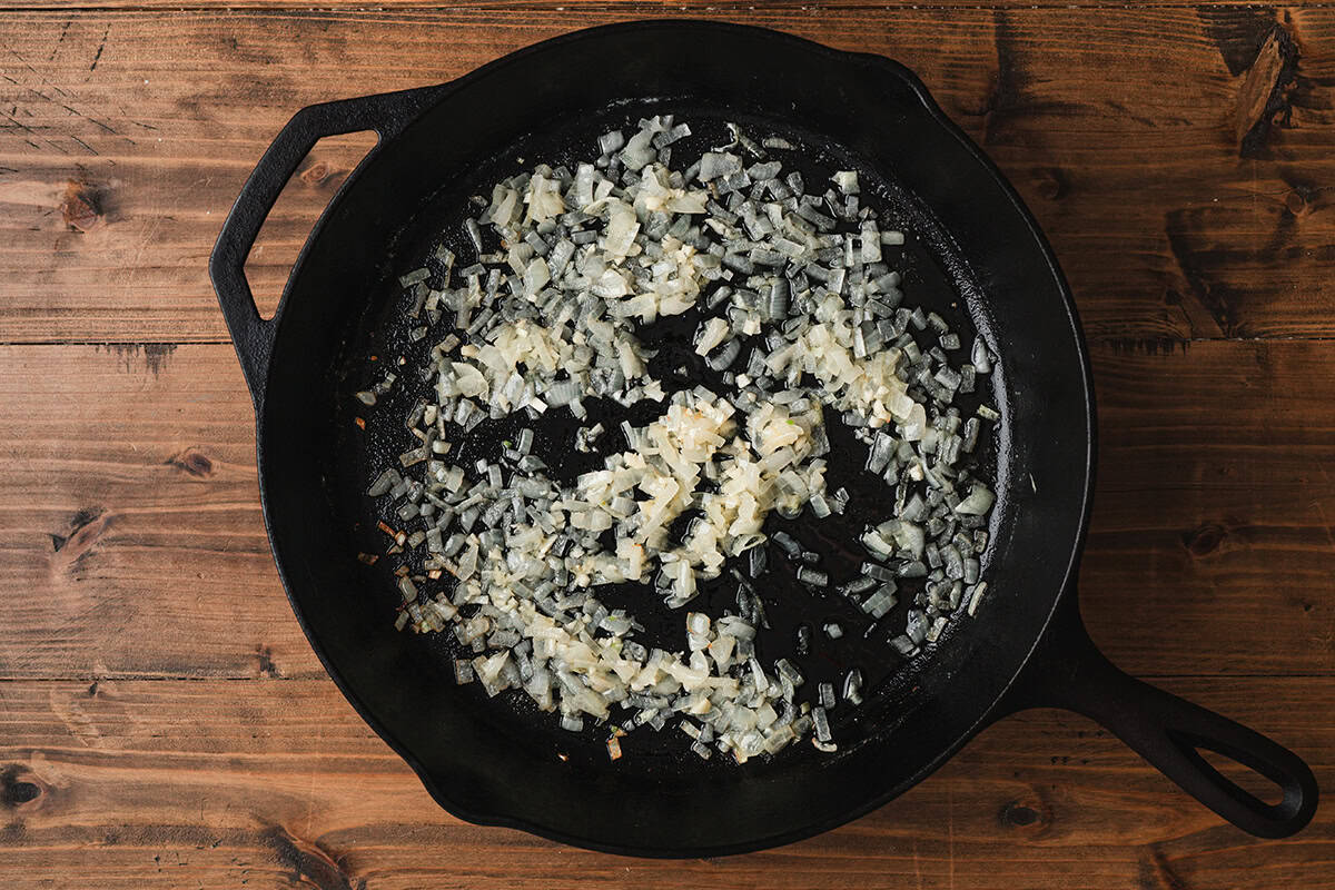 Diced sweet onions sautéing in butter in cast iron skillet for corned beef hash