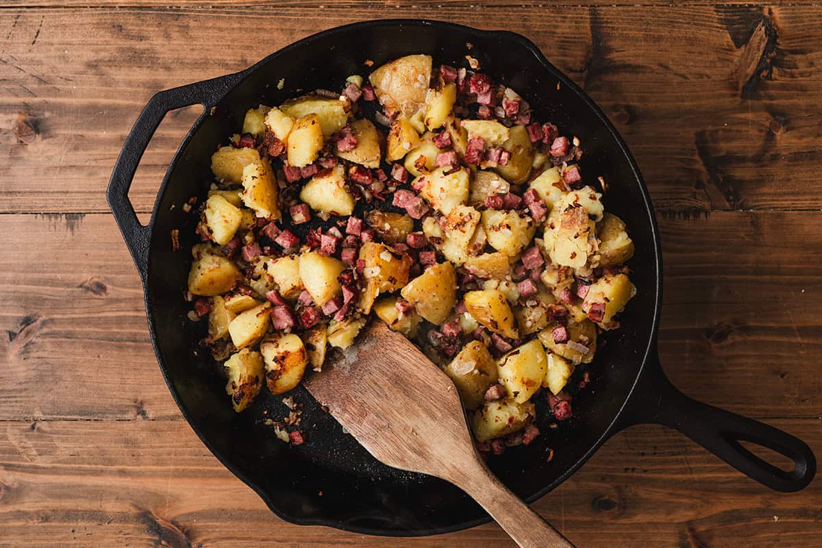 Corned beef hash cooking in skillet with potatoes browning and crisping on edges