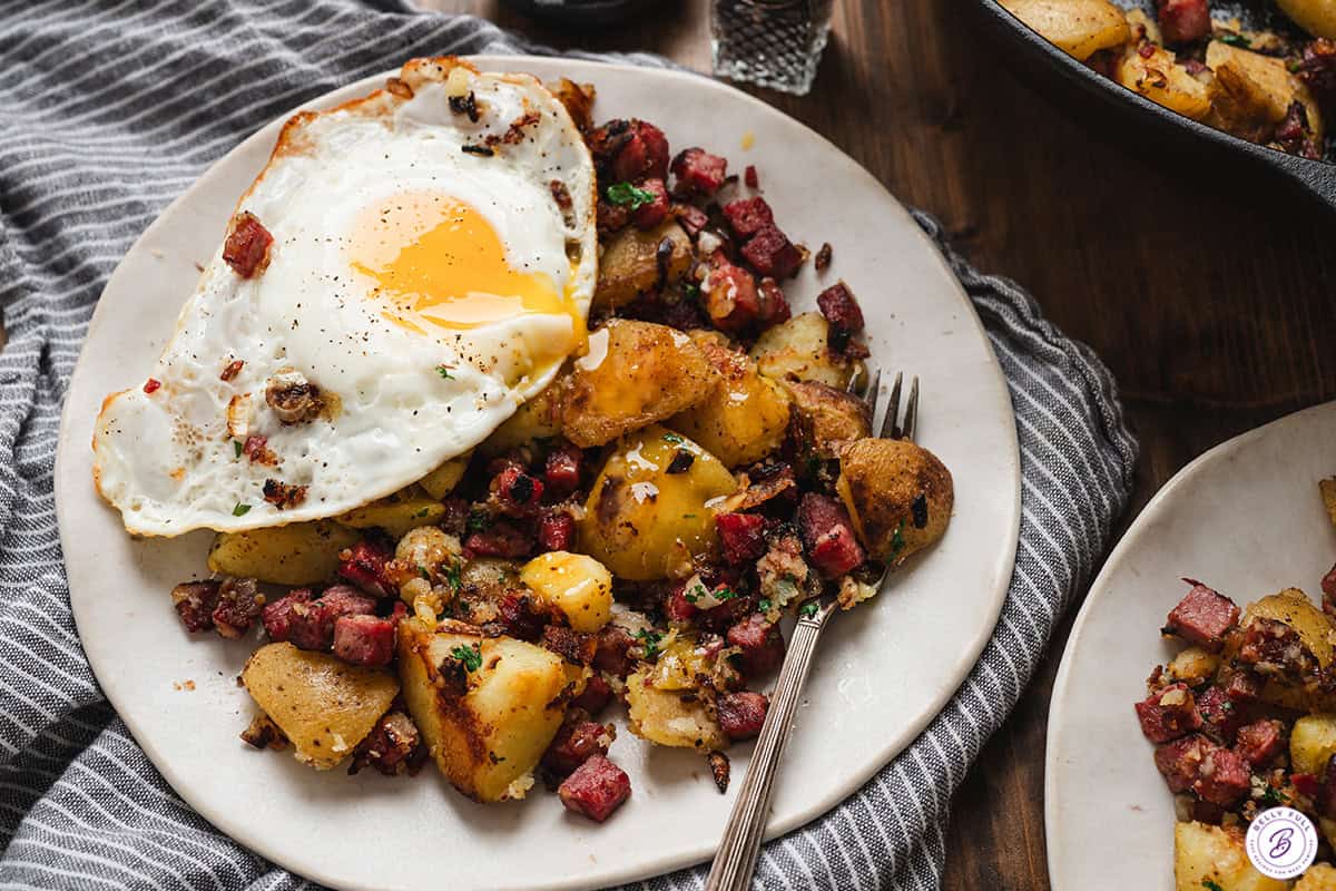Plated corned beef hash topped with fried egg and runny yolk