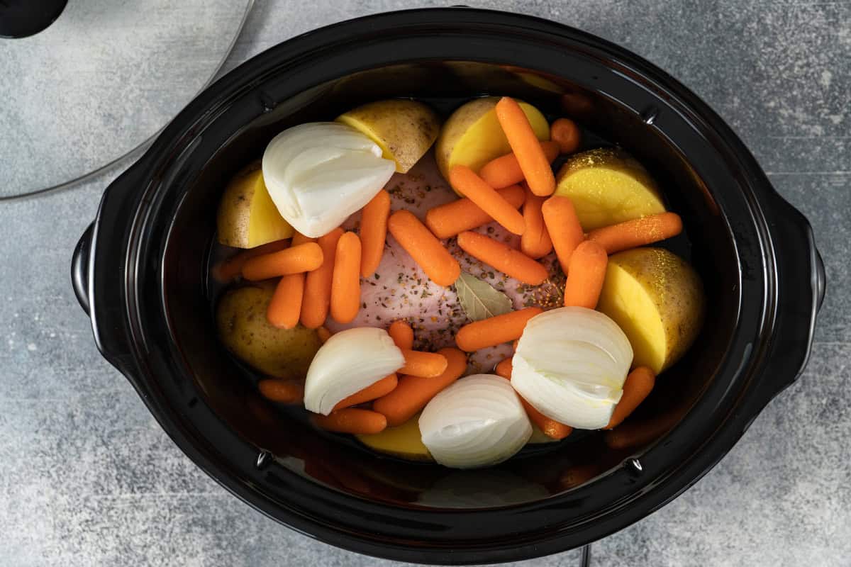 ingredients for corned beef and vegetables inside slow cooker insert