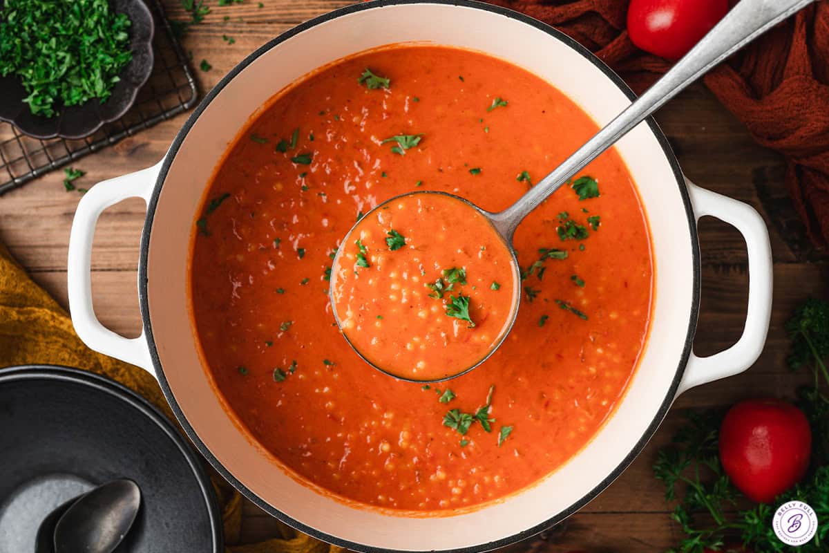 overhead ladle of tomato soup over pot