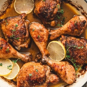 Balsamic lemon chicken thighs and drumsticks in a skillet with crispy lemon sugar skin, buttery pan sauce, lemon slices, and fresh thyme