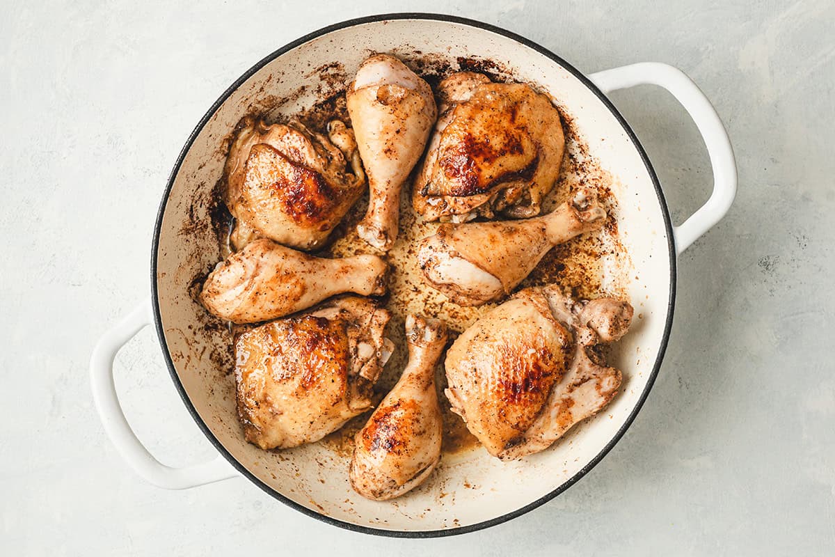 Chicken thighs and drumsticks searing skin-side down in a large skillet until golden brown