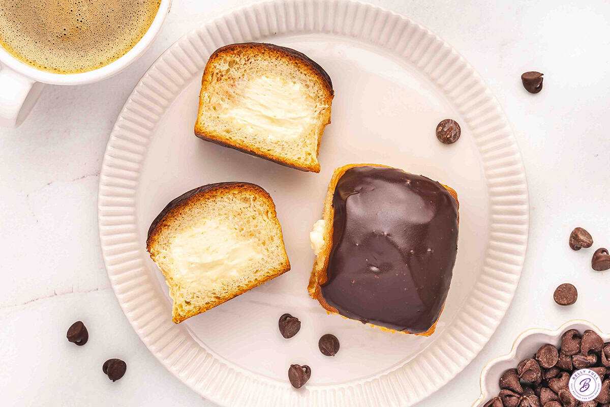 Overhead of two Side view of Boston cream roll pie 'donuts' on a plate with one cut open.