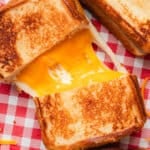 Overhead view of a copycat Disneyland grilled cheese sandwich sliced in half with melted cheese connecting the two halves.