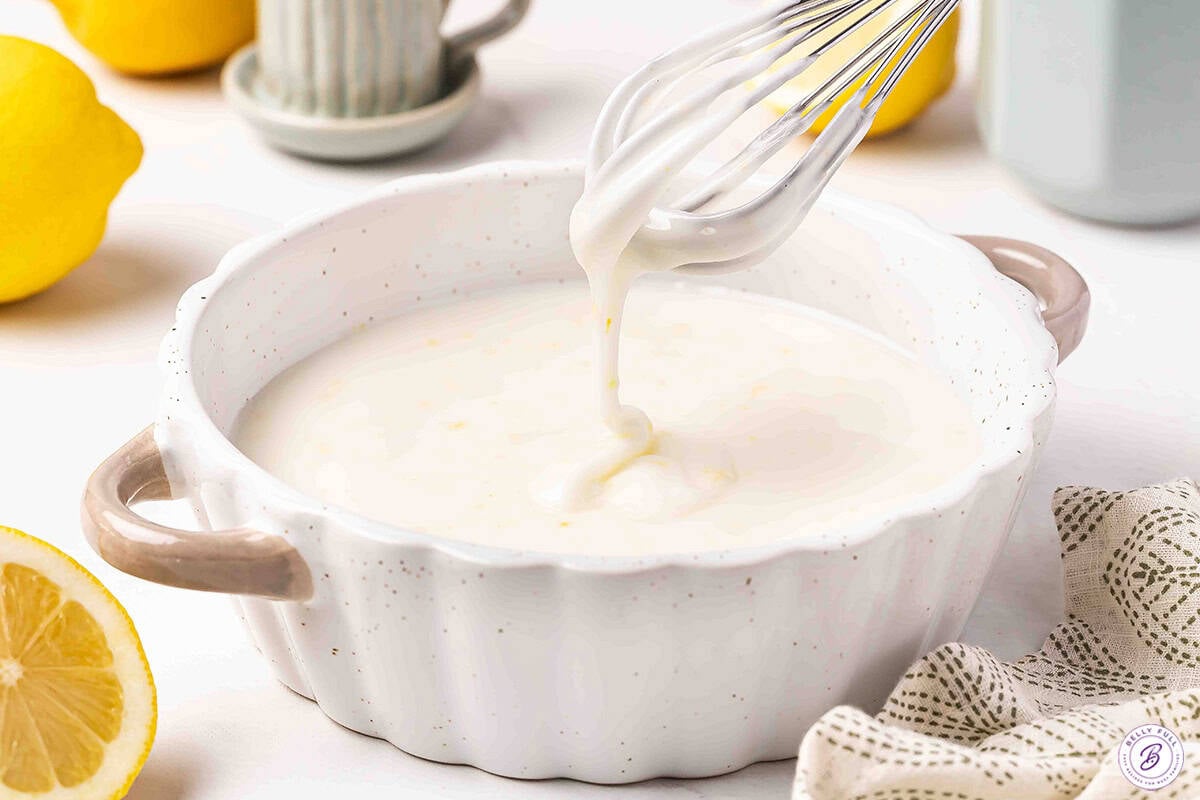 Lemon glaze in a dish with a whisk.