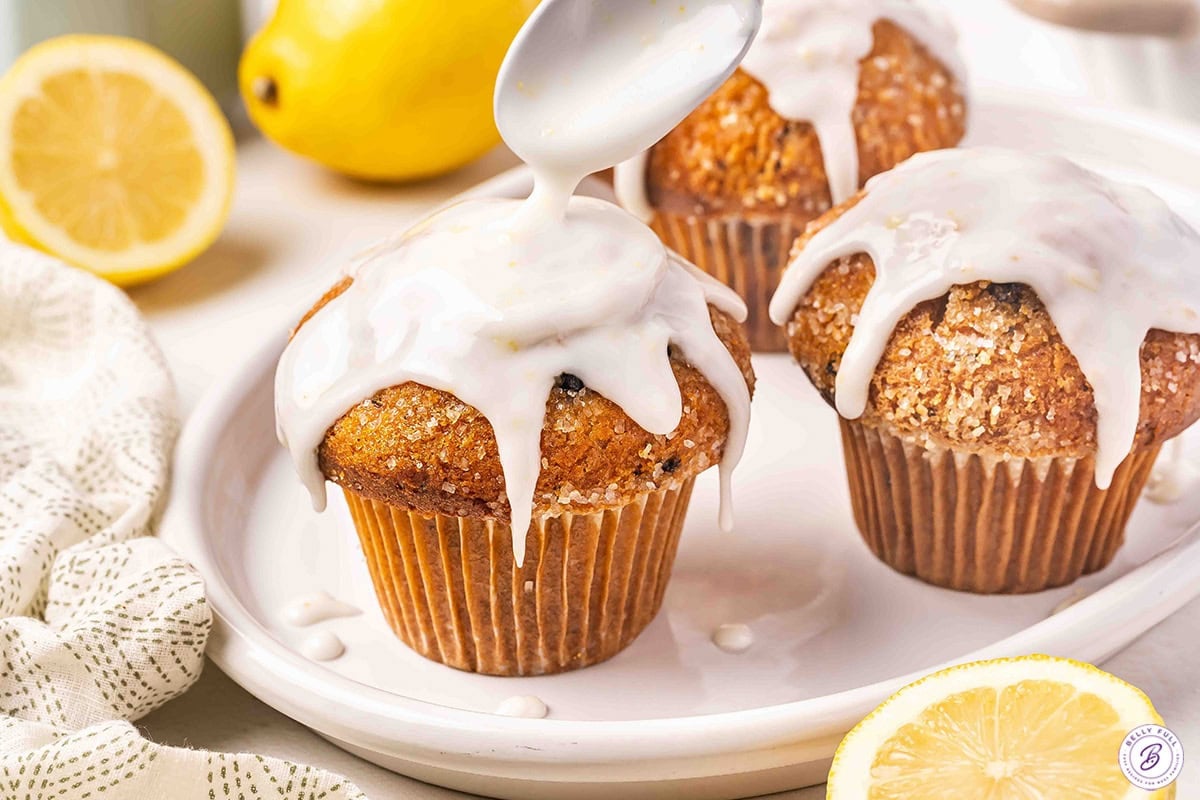 Lemon glaze being drizzled over muffins.