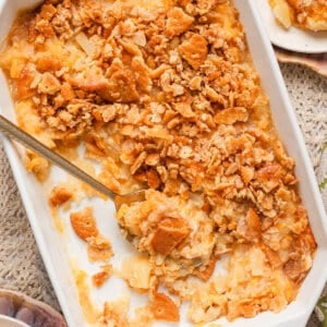 Overhead view of a southern pineapple casserole in a baking dish with a spoon and some of the casserole removed.