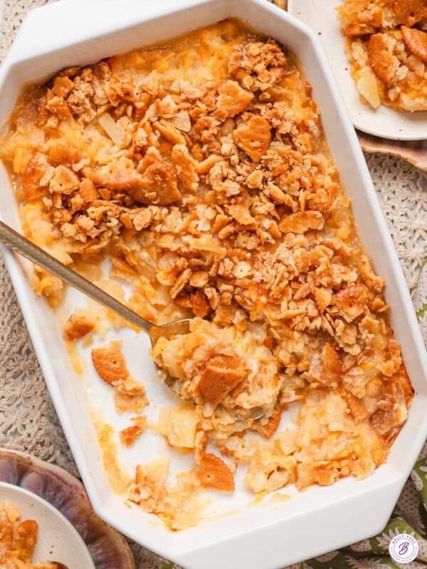 Overhead view of a southern pineapple casserole in a baking dish with a spoon and some of the casserole removed.