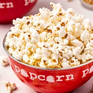 Stovetop popcorn piled high in a red popcorn bowl with fluffy freshly popped kernels.