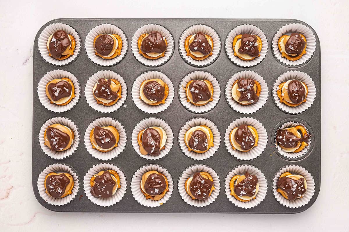 Peanut butter chocolate banana pretzel bites in a lined muffin pan, topped with flaky salt.