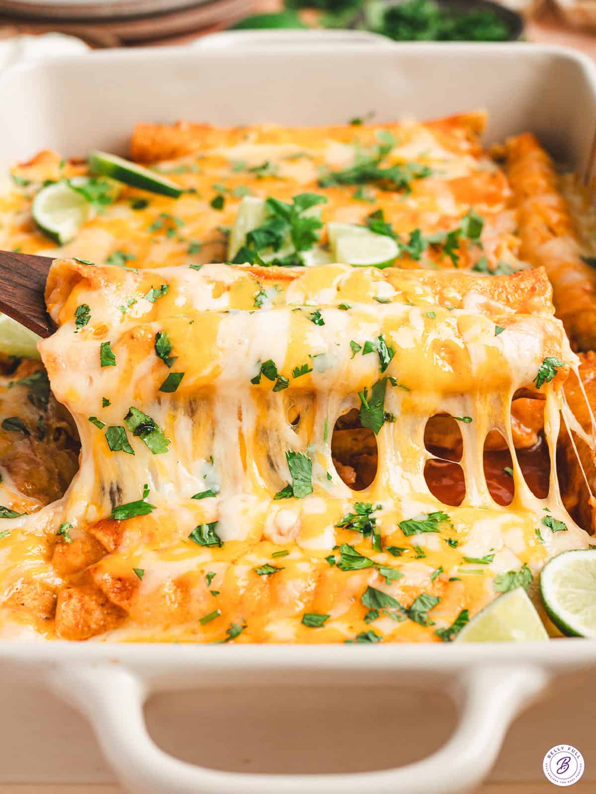 A spatula lifting lazy enchiladas out of a baking dish.