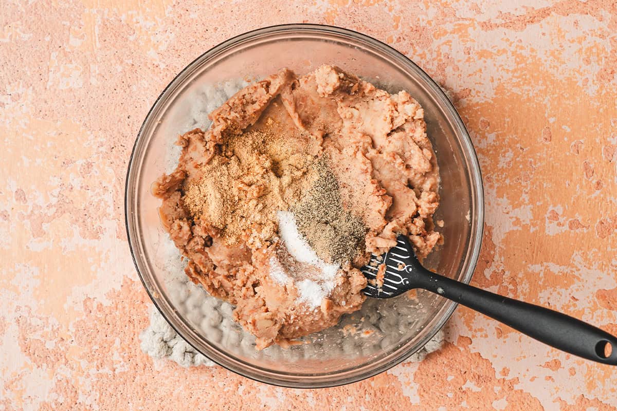 Refried beans in a bowl with seasonings.