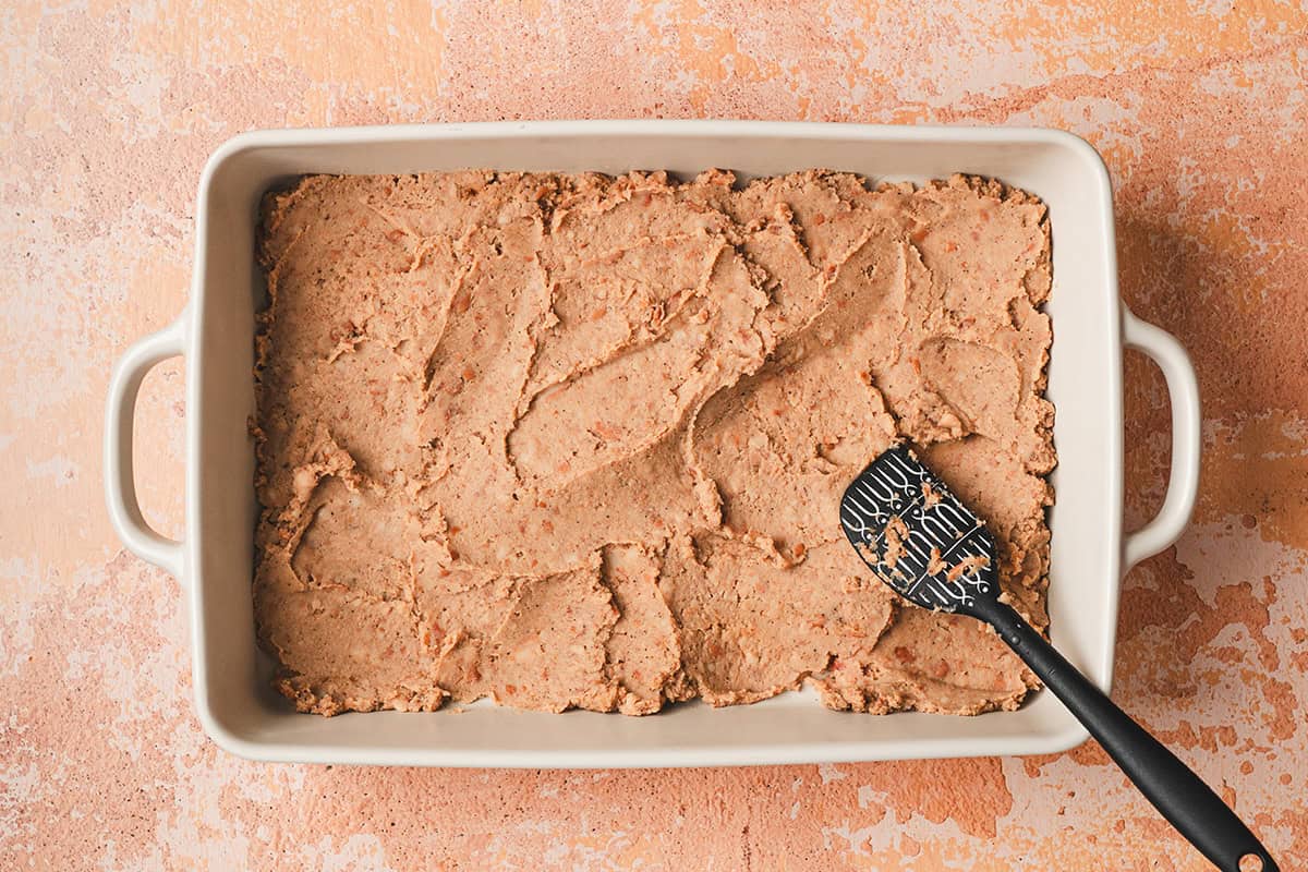Refried bean spread into a baking dish.