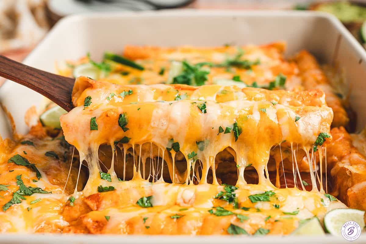 A spatula lifting lazy echiladas out of a baking dish.