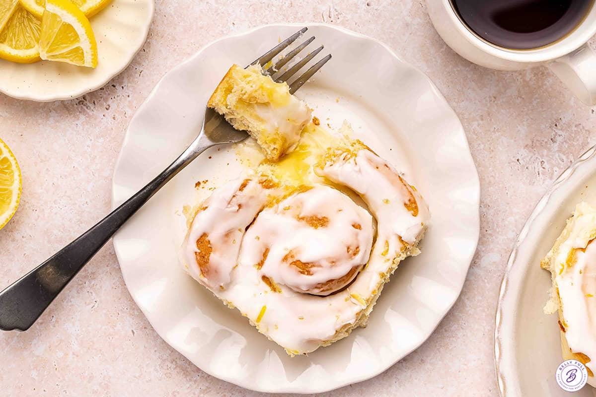 Overview of a lemon roll on a plate with a piece missing.