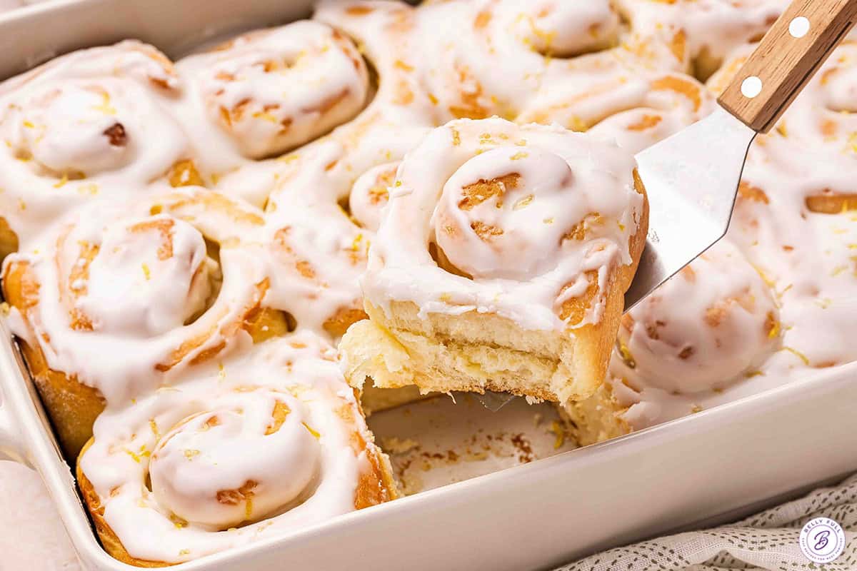 A lemon sweet roll being lifted out the pan.