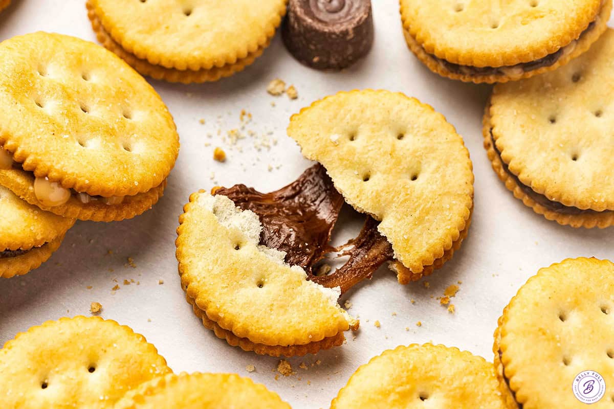 A rolo ritz sandwich cookie broken in half with a caramel pull.
