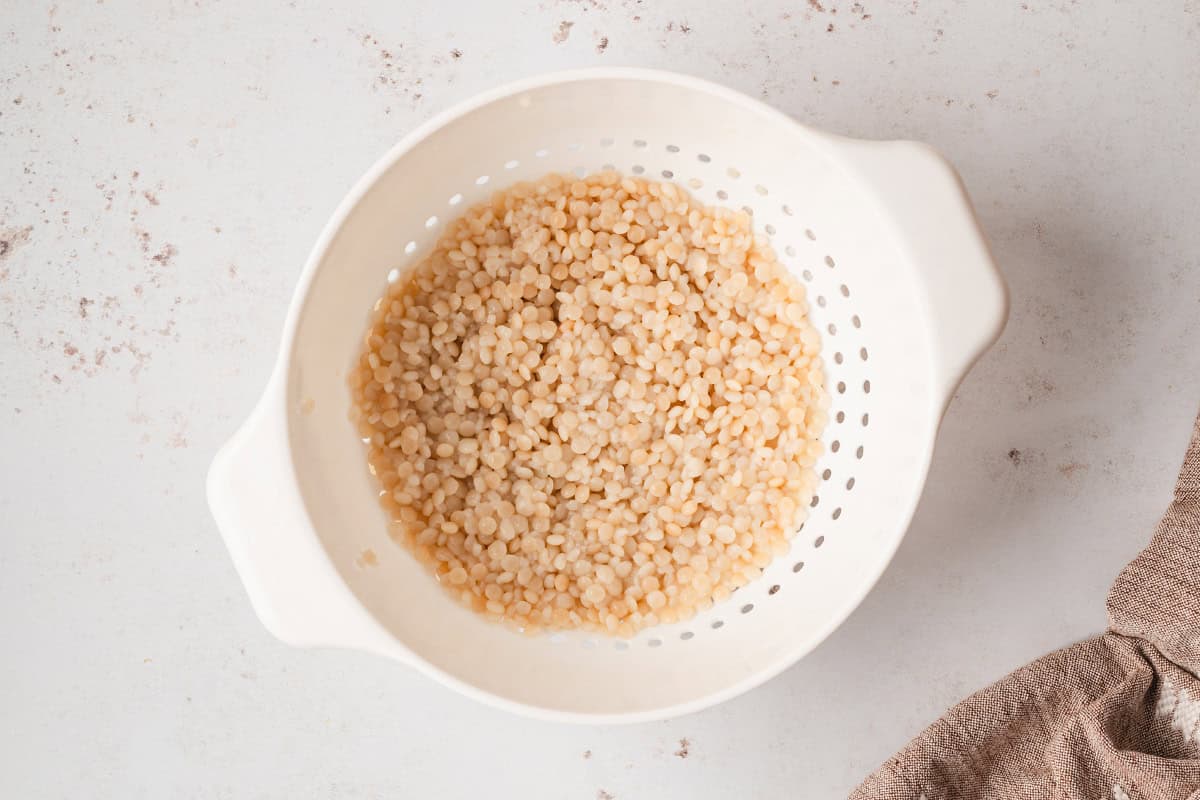 cooked and cooled Israeli pearl couscous in strainer
