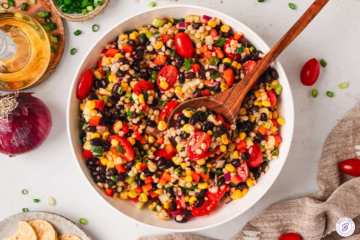 cowboy caviar couscous salad in bowl with serving spoon