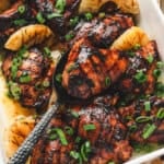 Grilled Hawaiian chicken thighs with charred pineapple and green onions in a serving dish