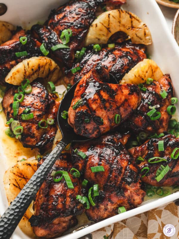 Grilled Hawaiian chicken thighs with charred pineapple and green onions in a serving dish