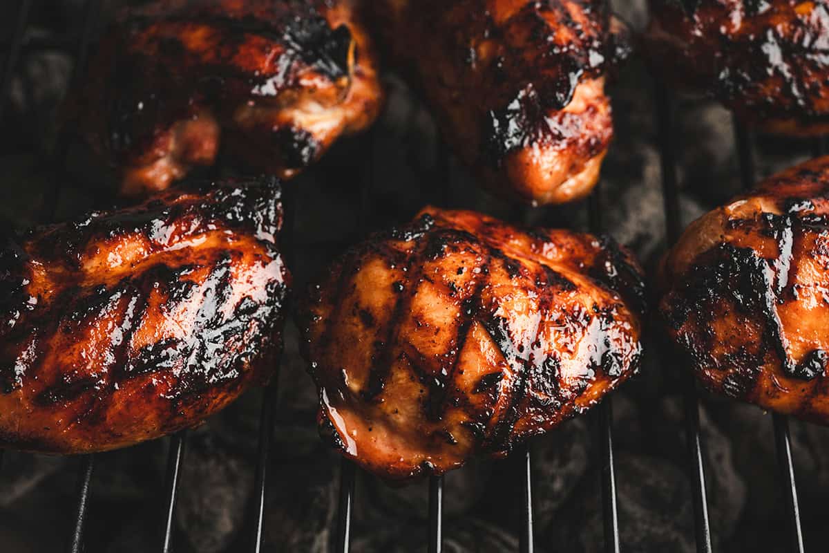 Hawaiian barbecue chicken thighs grilling with caramelized glaze and charred edges