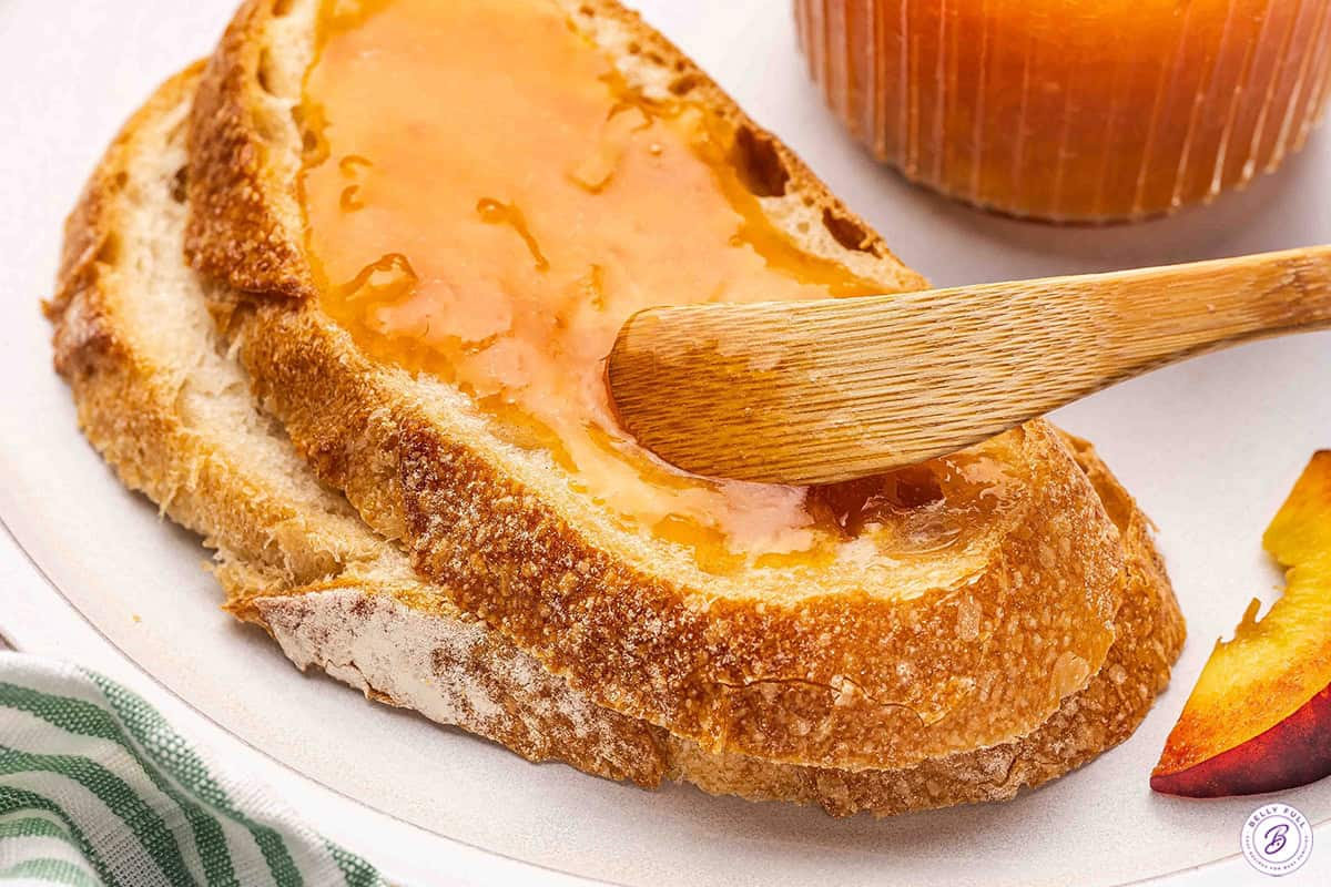 Slice of crusty bread spread with homemade peach jam