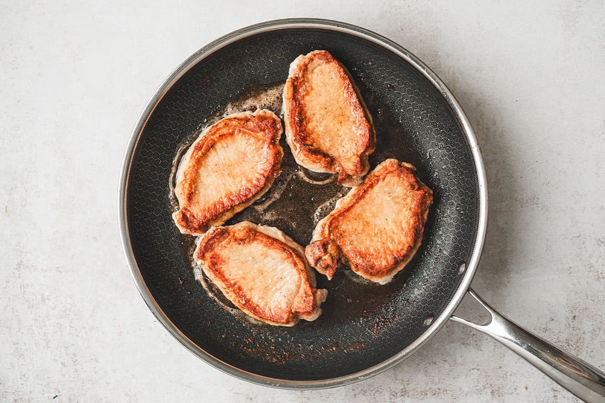 Boneless pork loin chops in a skillet.