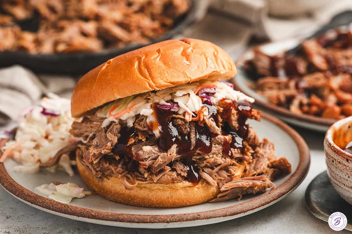 Pulled pork sandwich piled high on a brioche bun with coleslaw and barbecue sauce.