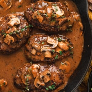 Salisbury steak patties simmered in rich mushroom onion gravy in a cast iron skillet.