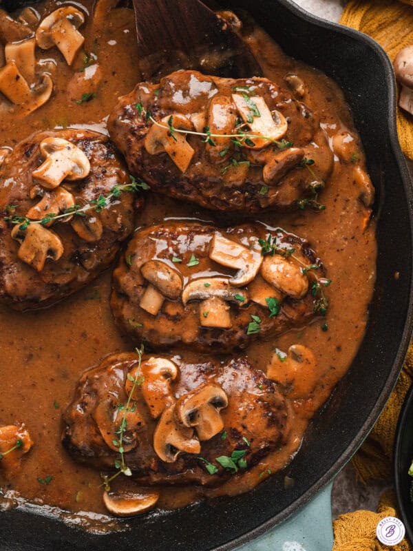 Salisbury steak patties simmered in rich mushroom onion gravy in a cast iron skillet.