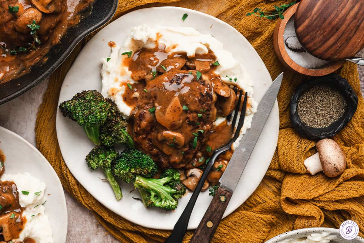 Salisbury steak with mushroom gravy served over mashed potatoes with roasted broccoli on the side.