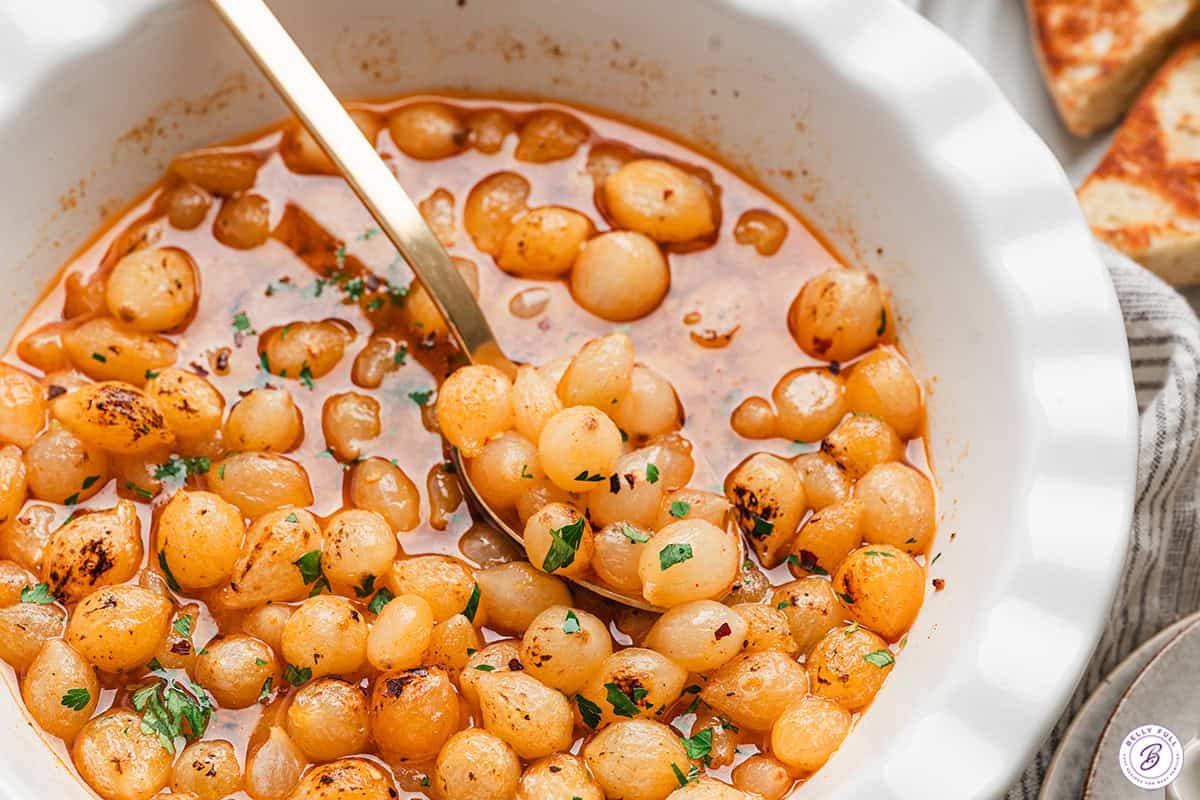 Close up of mini pearl onion boil with a spoon.