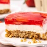 Side view of a slice of strawberry pretzel salad on a plate.