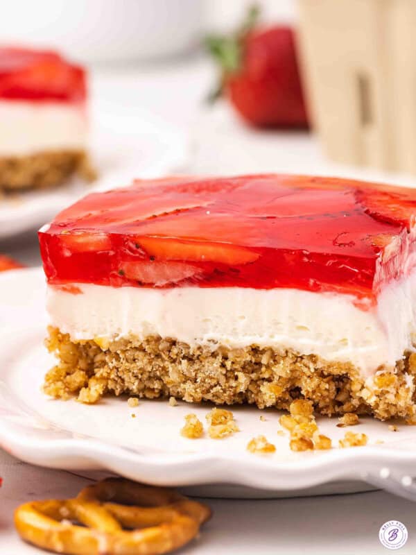 Side view of a slice of strawberry pretzel salad on a plate.