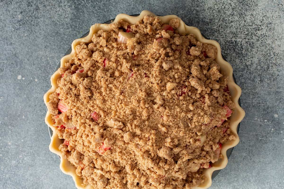 Strawberry rhubarb pie assembled with fruit filling and crumb topping before baking.