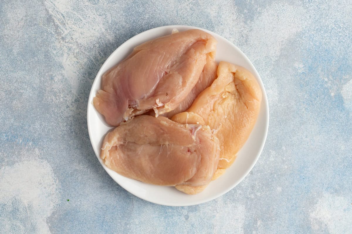 raw boneless skinless chicken breasts on white plate