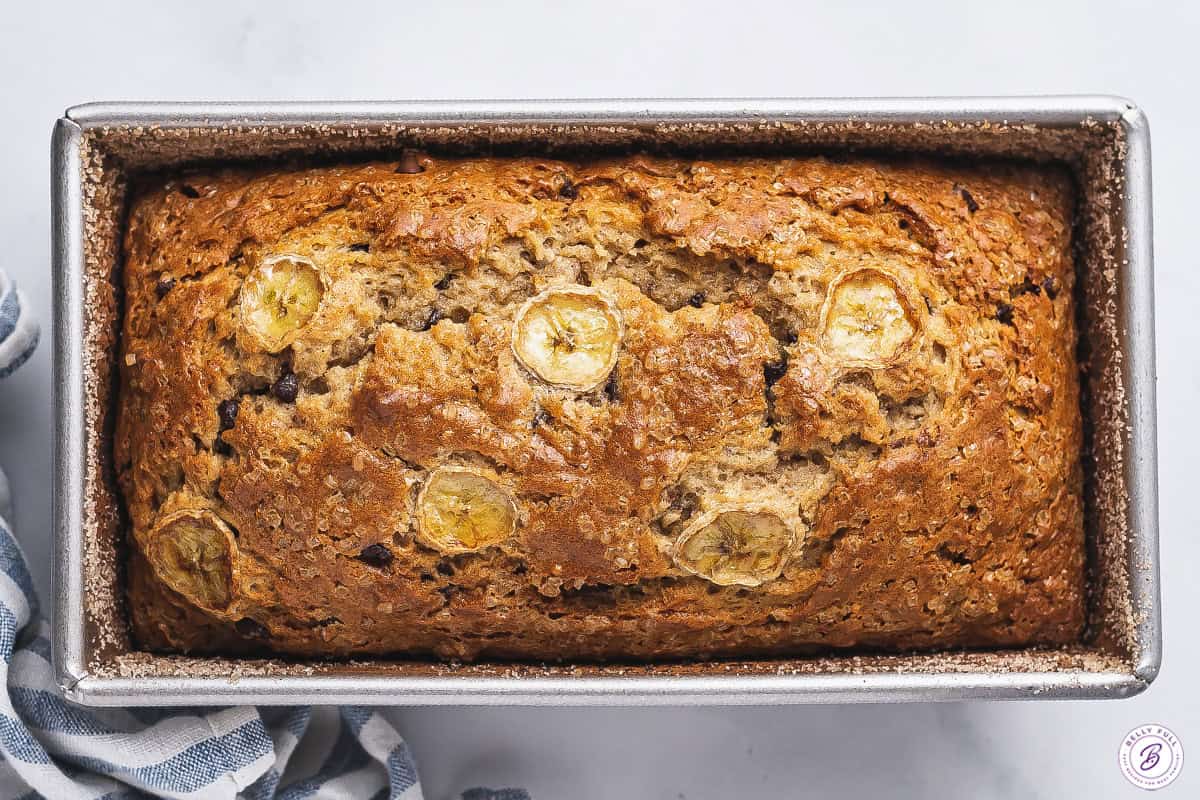 overhead of baked banana bread in loaf pan with sliced banana on top