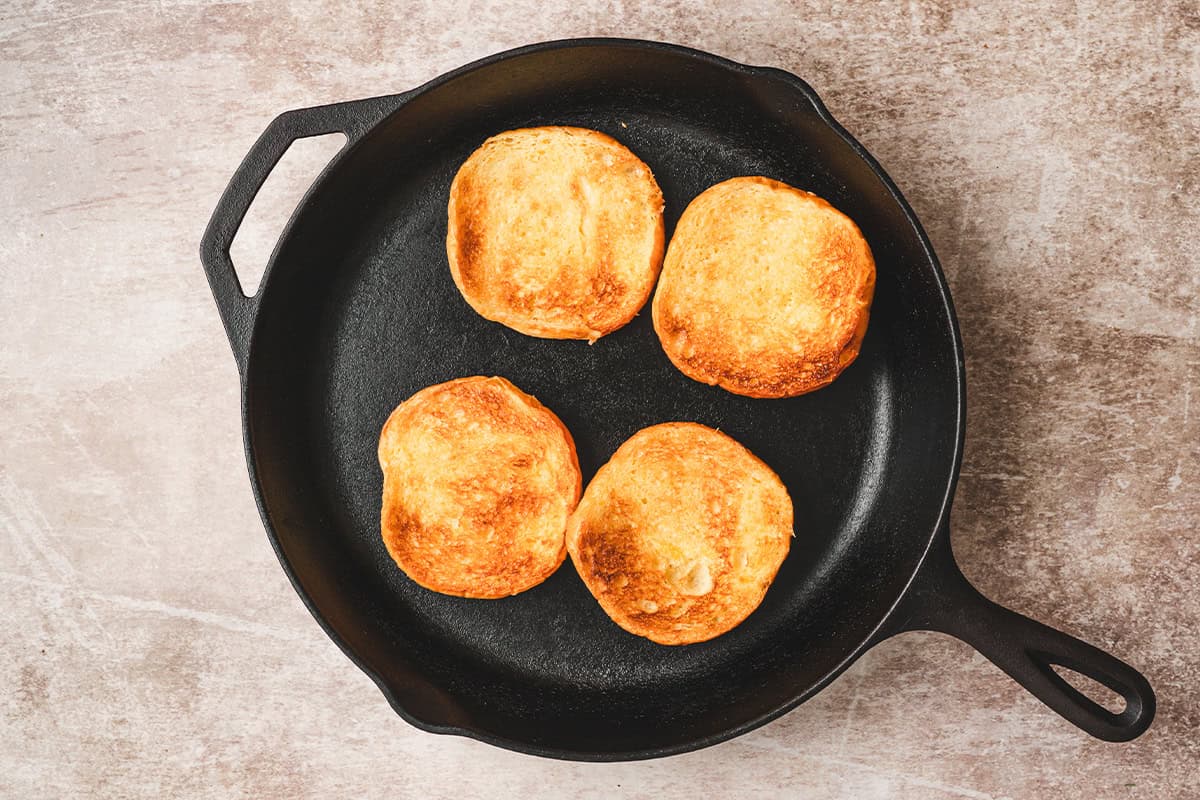 Hamburger buns toasting in a skillet.