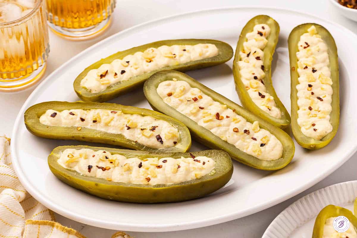 Deviled pickles on a plate topped with red pepper flakes and crushed potato chips.