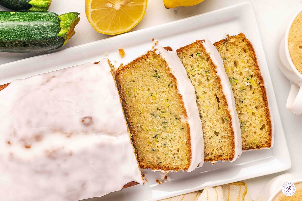 Overhead view of a lemon zucchini loaf with half cut into slices.