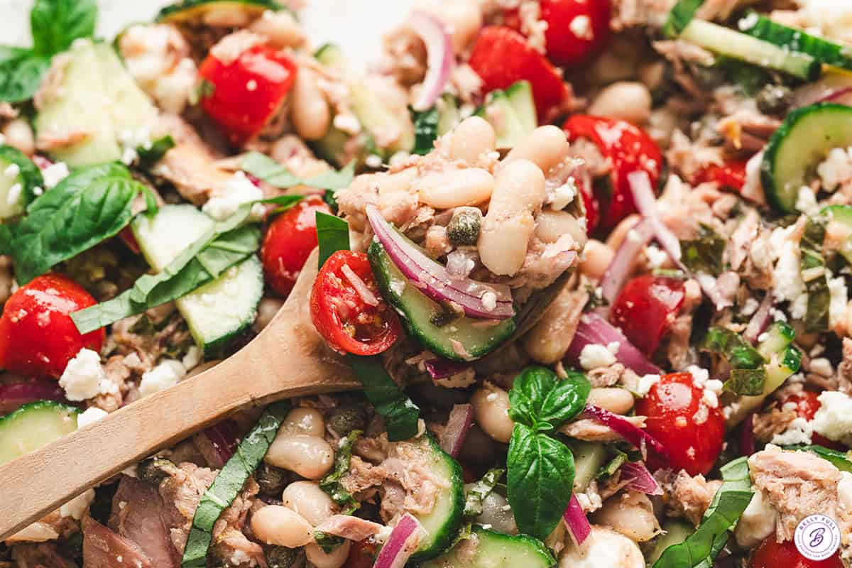 Close up of tuna white bean salad on a wooden spoon.