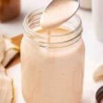 Yum Yum Sauce drizzling off a spoon into a mason jar, showing its smooth, pourable consistency