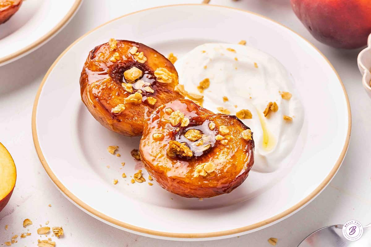 Side view of air fryer peaches on a plate with granola and yogurt.