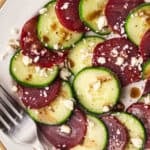 overhead cucumber beet salad with feta and balsamic dressing on a white plate with a fork