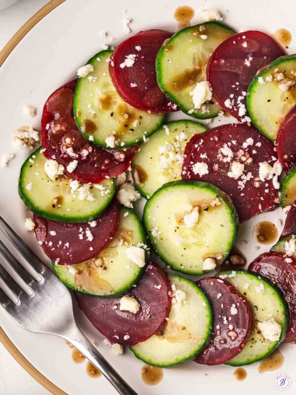 overhead cucumber beet salad with feta and balsamic dressing on a white plate with a fork