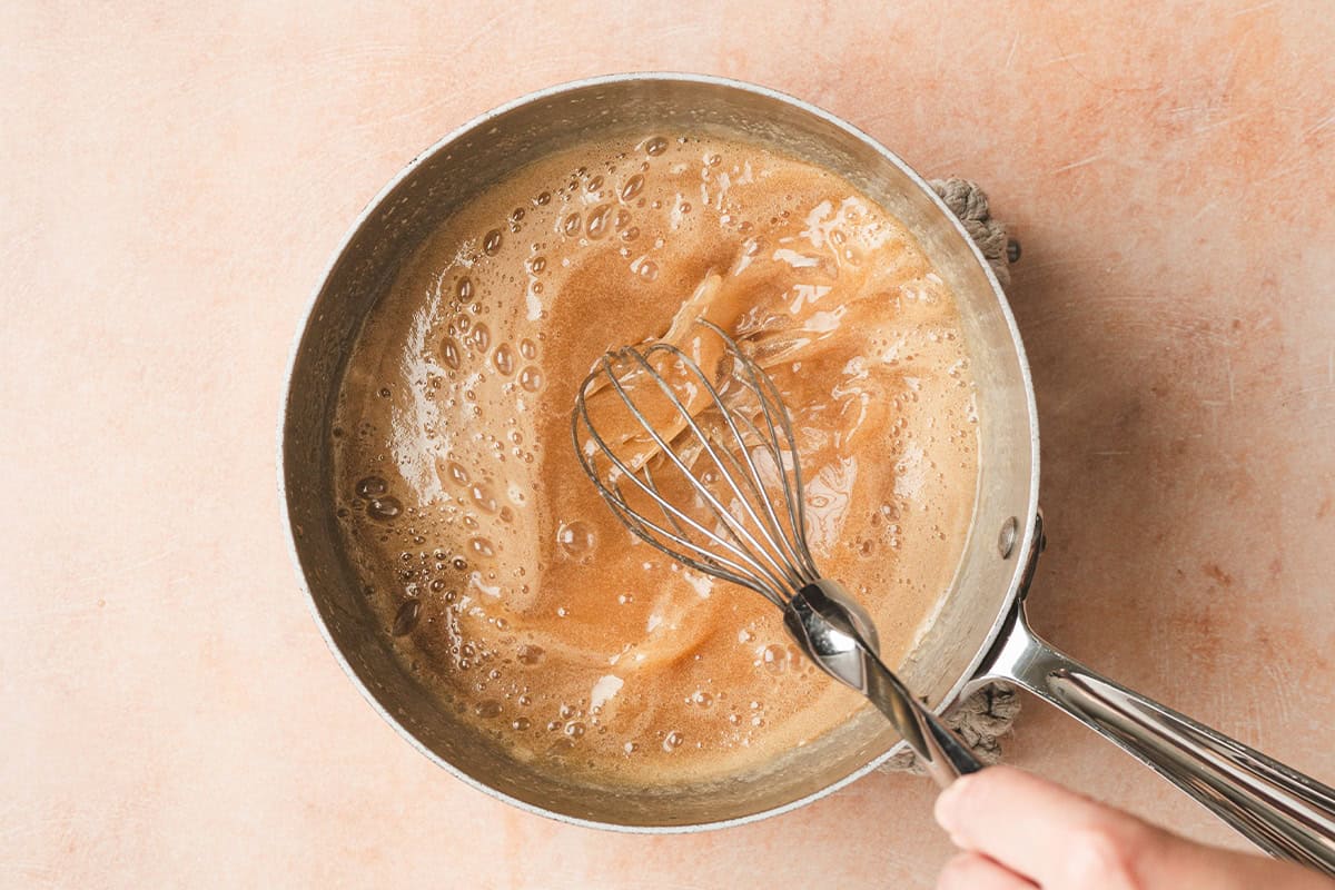 Foaming maple butter syrup in a sauce pan being whisked.